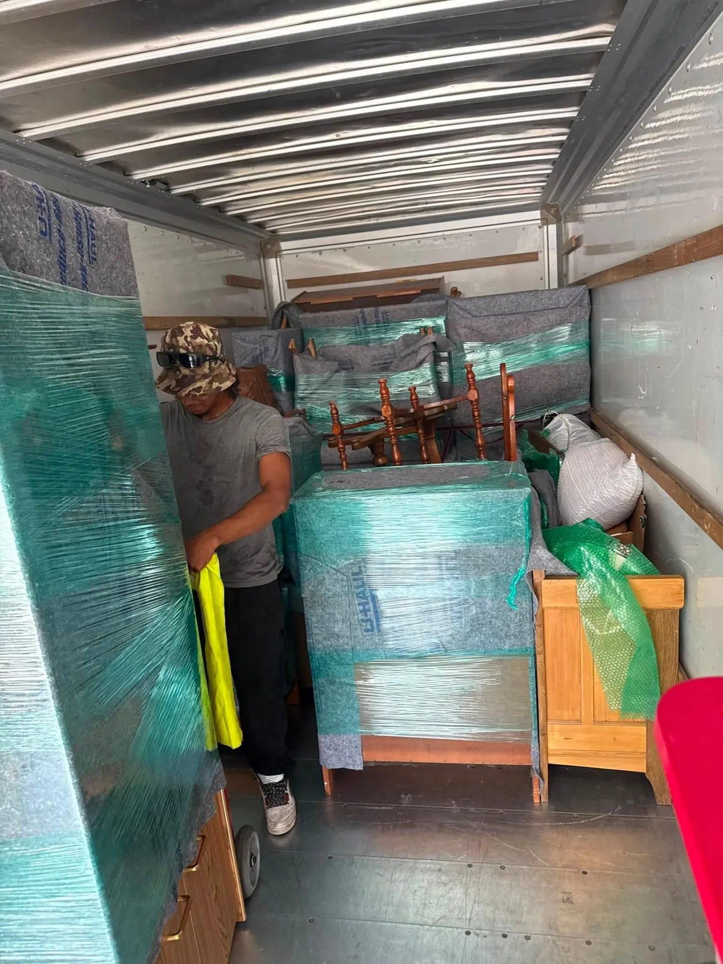 Crew member shrink-wrapping furniture inside the truck
