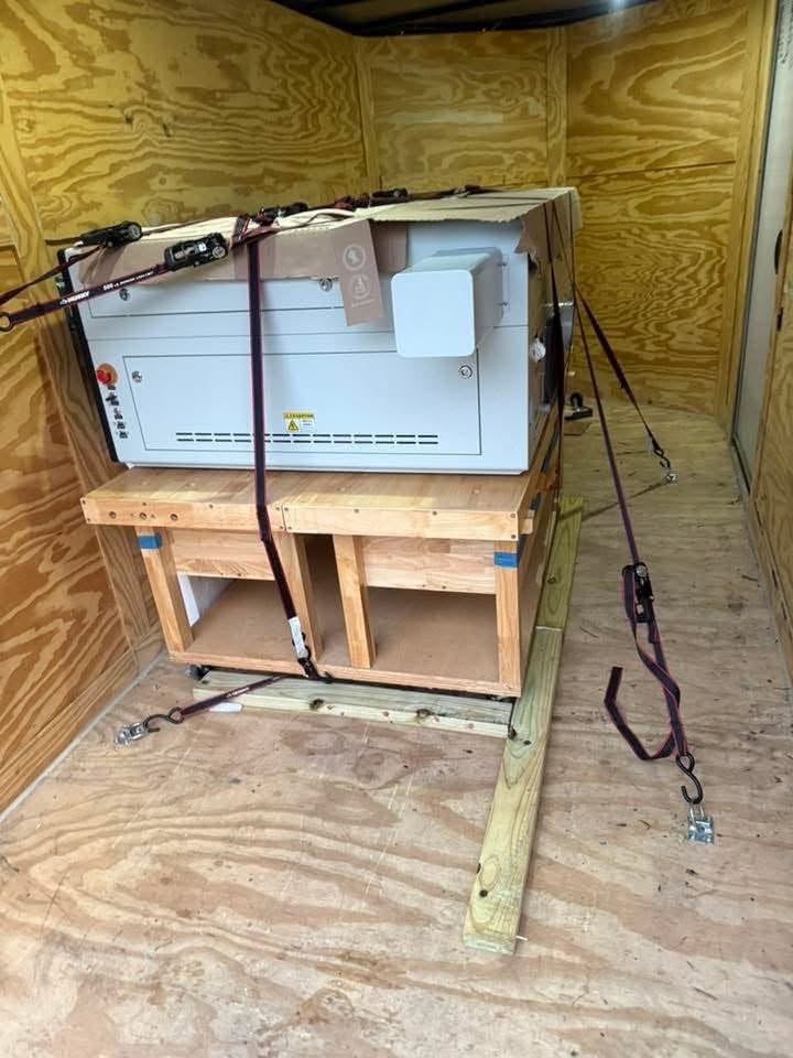 Large industrial machine crated and ratchet-strapped inside the trailer