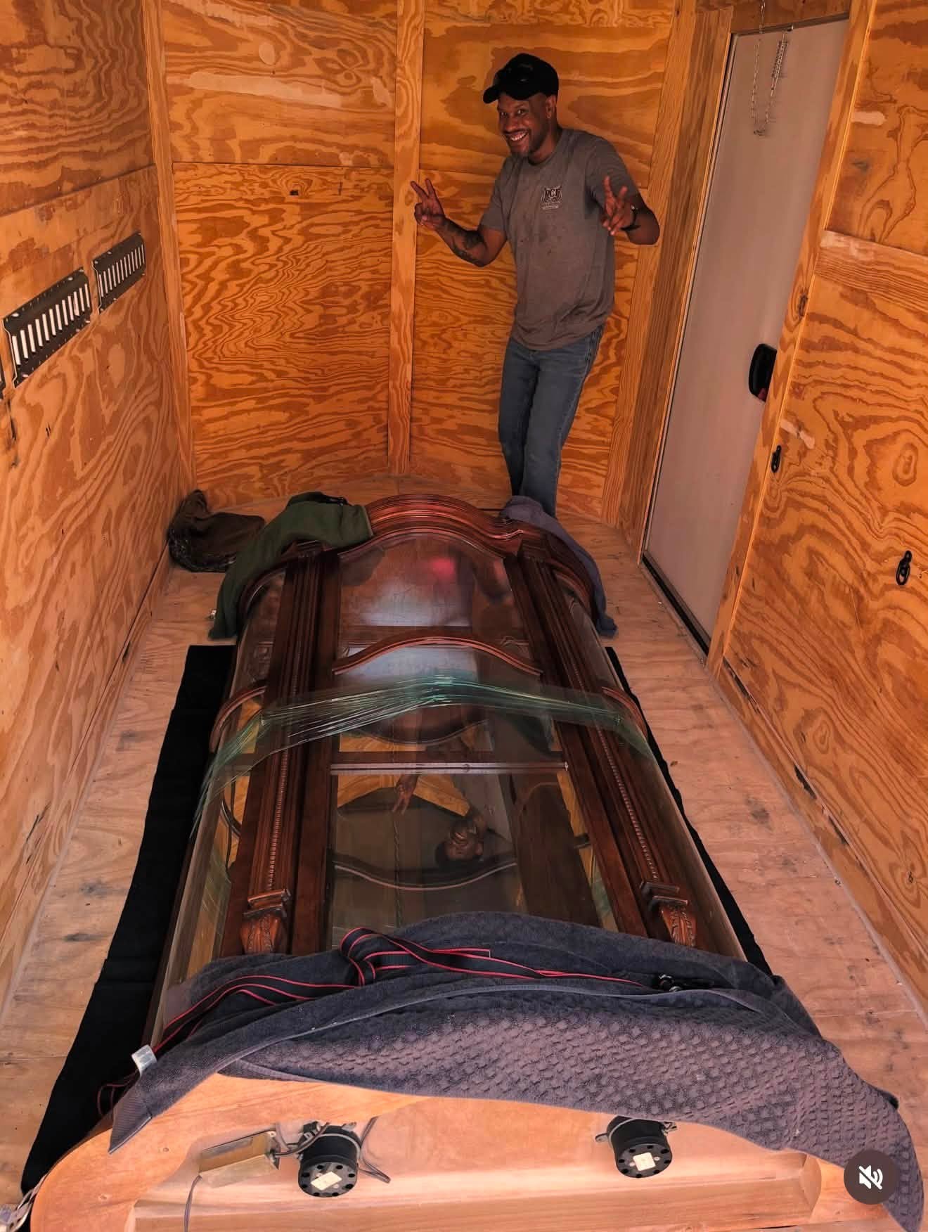 RCFC crew member with a large antique glass curio cabinet padded and strapped inside the trailer